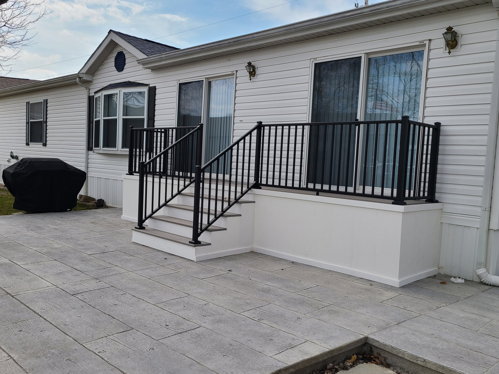 Stamped concrete patio with new steps and black aluminum railing