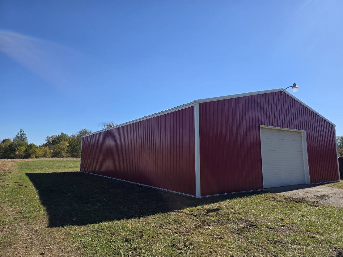 Large red pole barn with white trim and overhead door built by T&J Construction in Northern Indiana