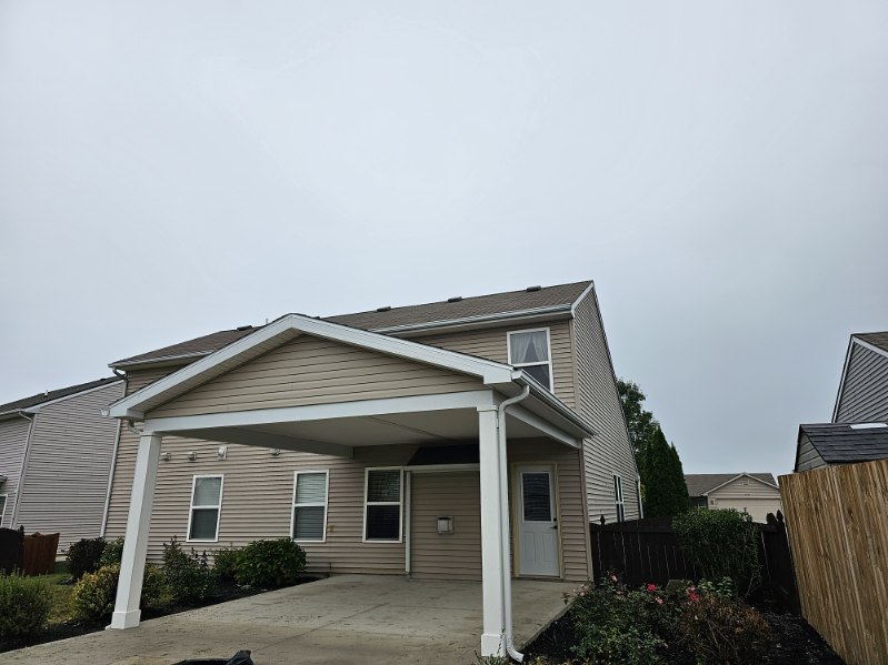 Covered concrete patio with white columns and shingled gable roof addition