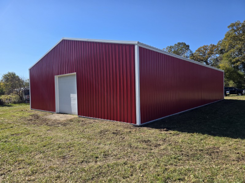 Large red pole barn with white overhead door built by a Northern Indiana pole barn builder