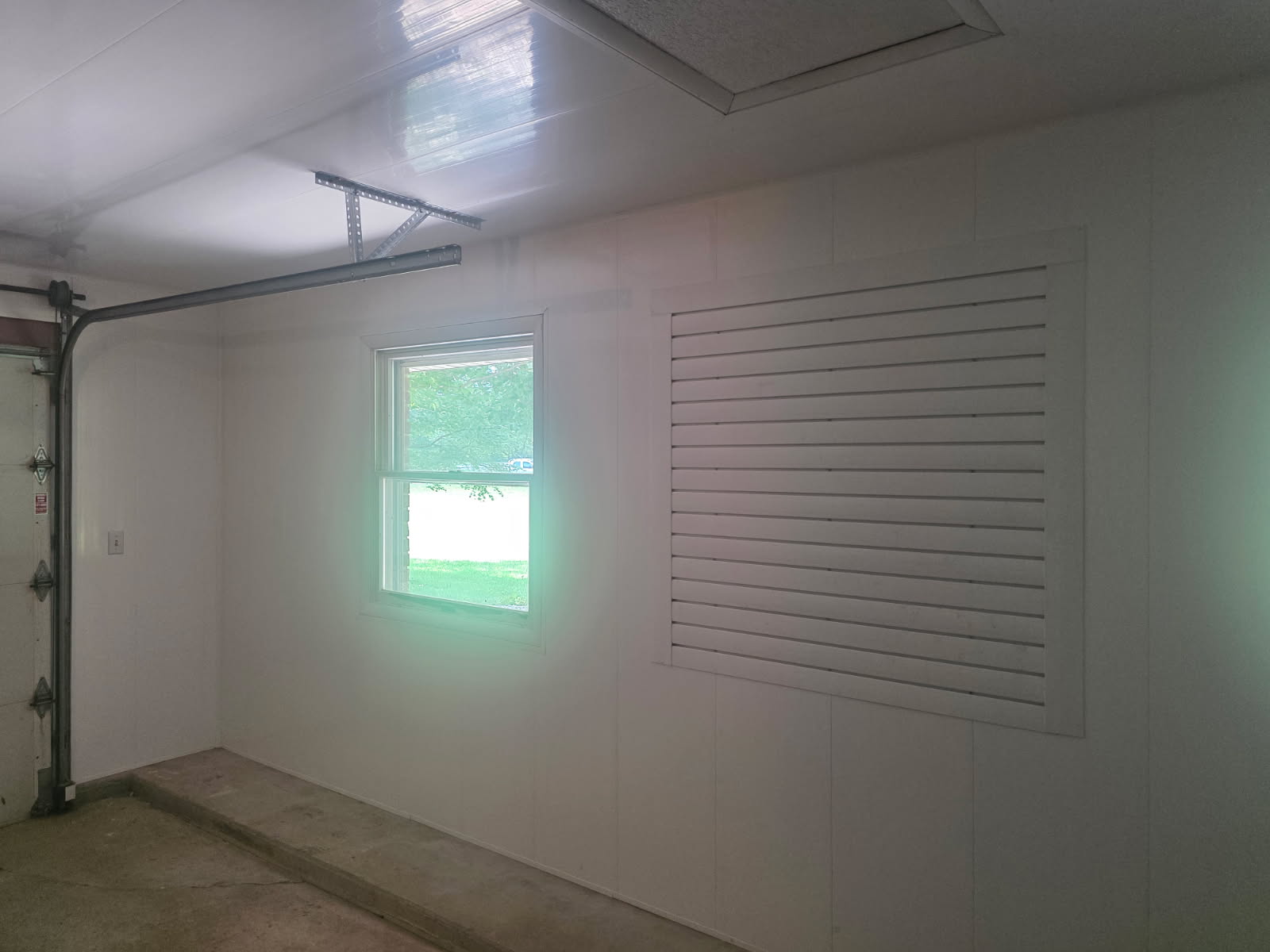 Finished garage interior with new window and painted wall paneling