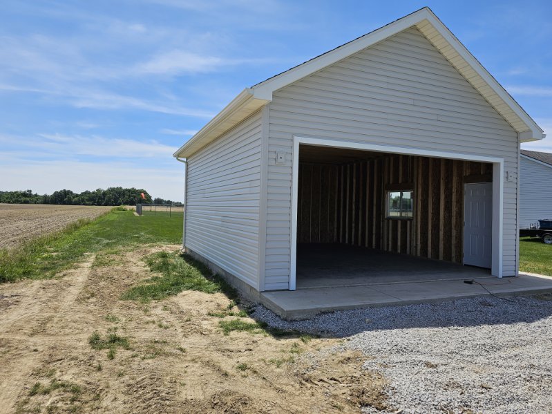 New white pole barn garage with open overhead door and concrete apron