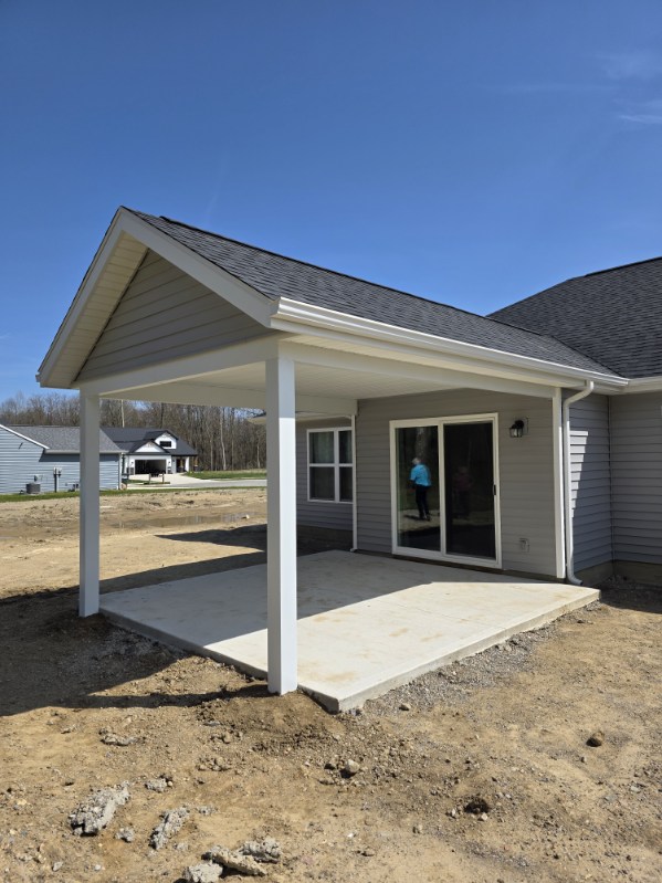 New covered concrete patio addition with gable roof and white columns