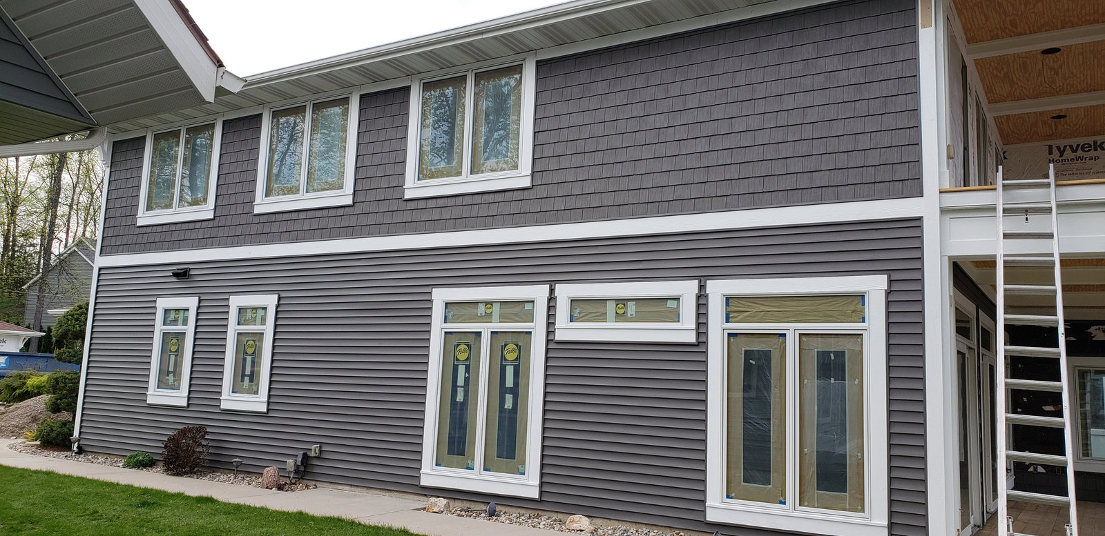 Two story home with new gray shake and lap vinyl siding installed by a siding contractor