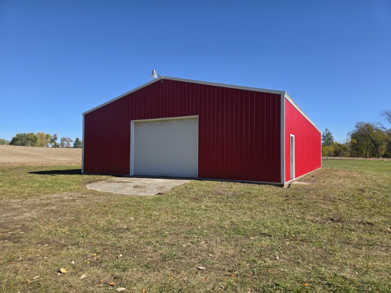 Red pole barn with white overhead garage door and concrete apron in Northern Indiana