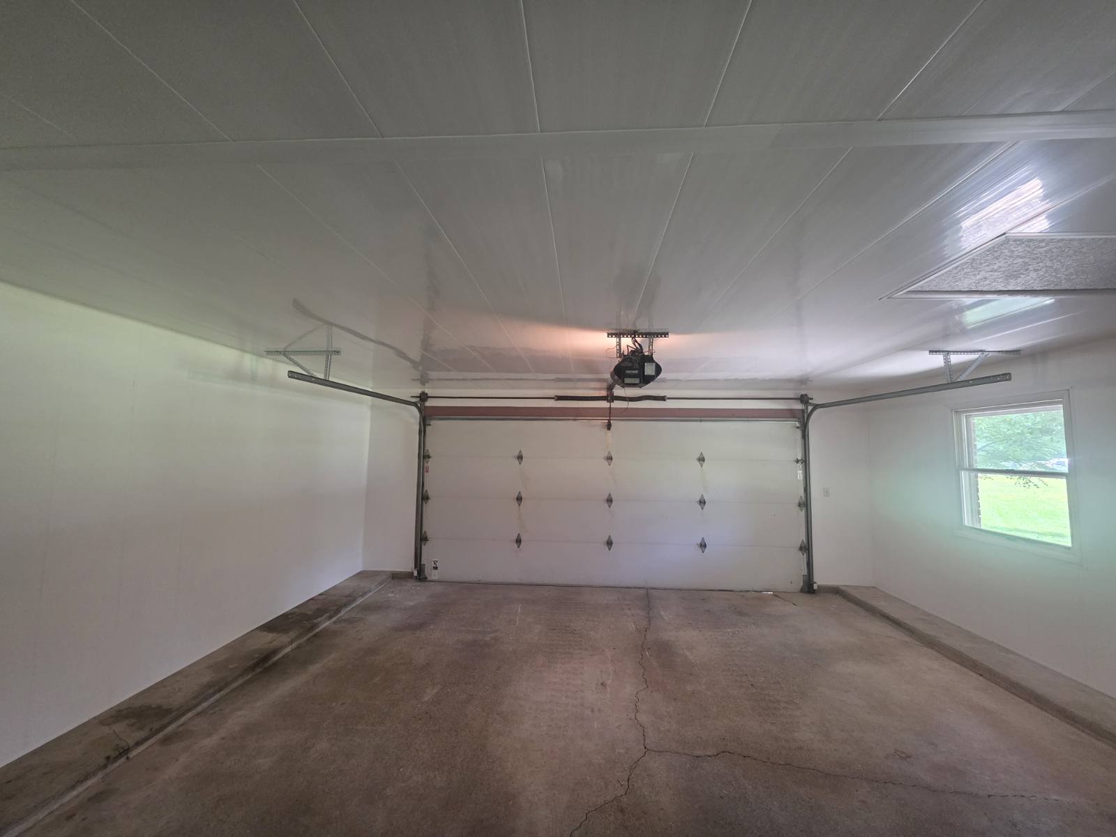 Bright finished garage interior with insulated overhead door and painted panel walls