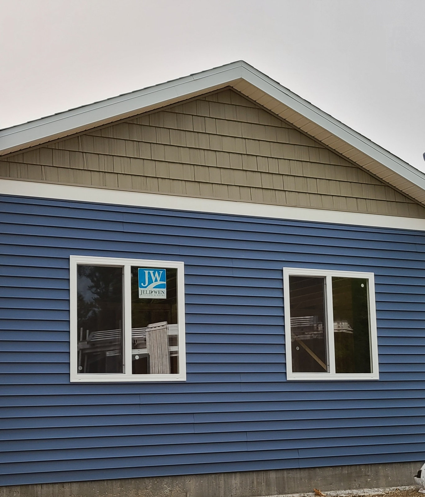 Blue vinyl siding with new energy efficient windows installed by T&J Construction