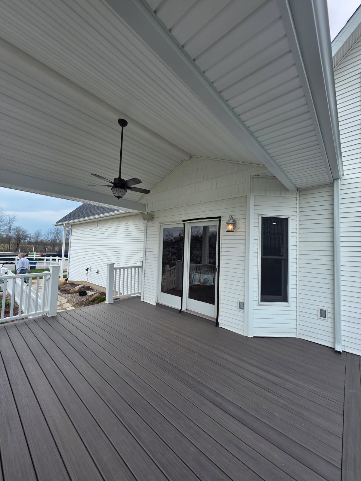 Covered composite deck with vaulted white beadboard ceiling and sliding patio door