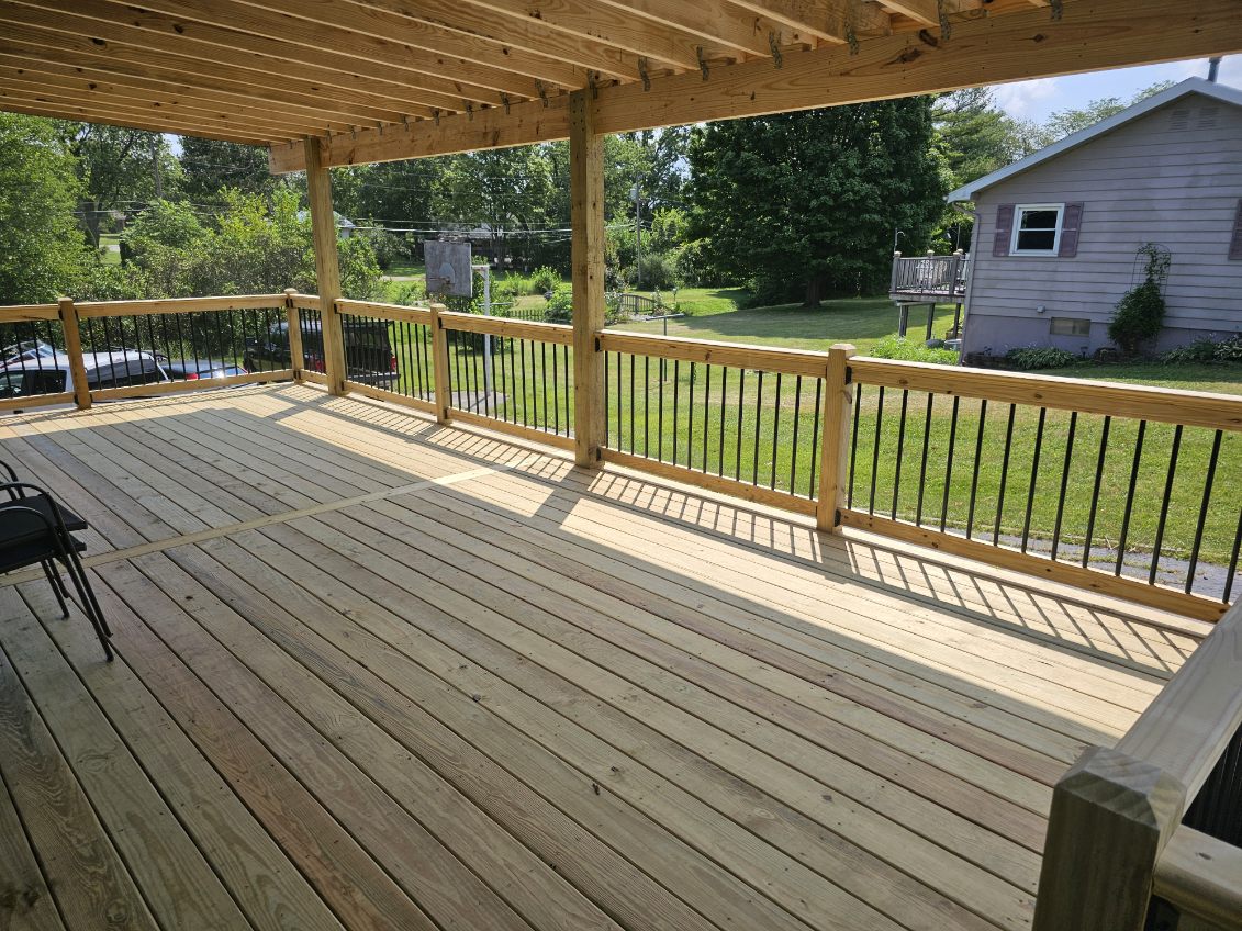 Covered pressure treated deck with wood posts and black metal balusters overlooking the yard