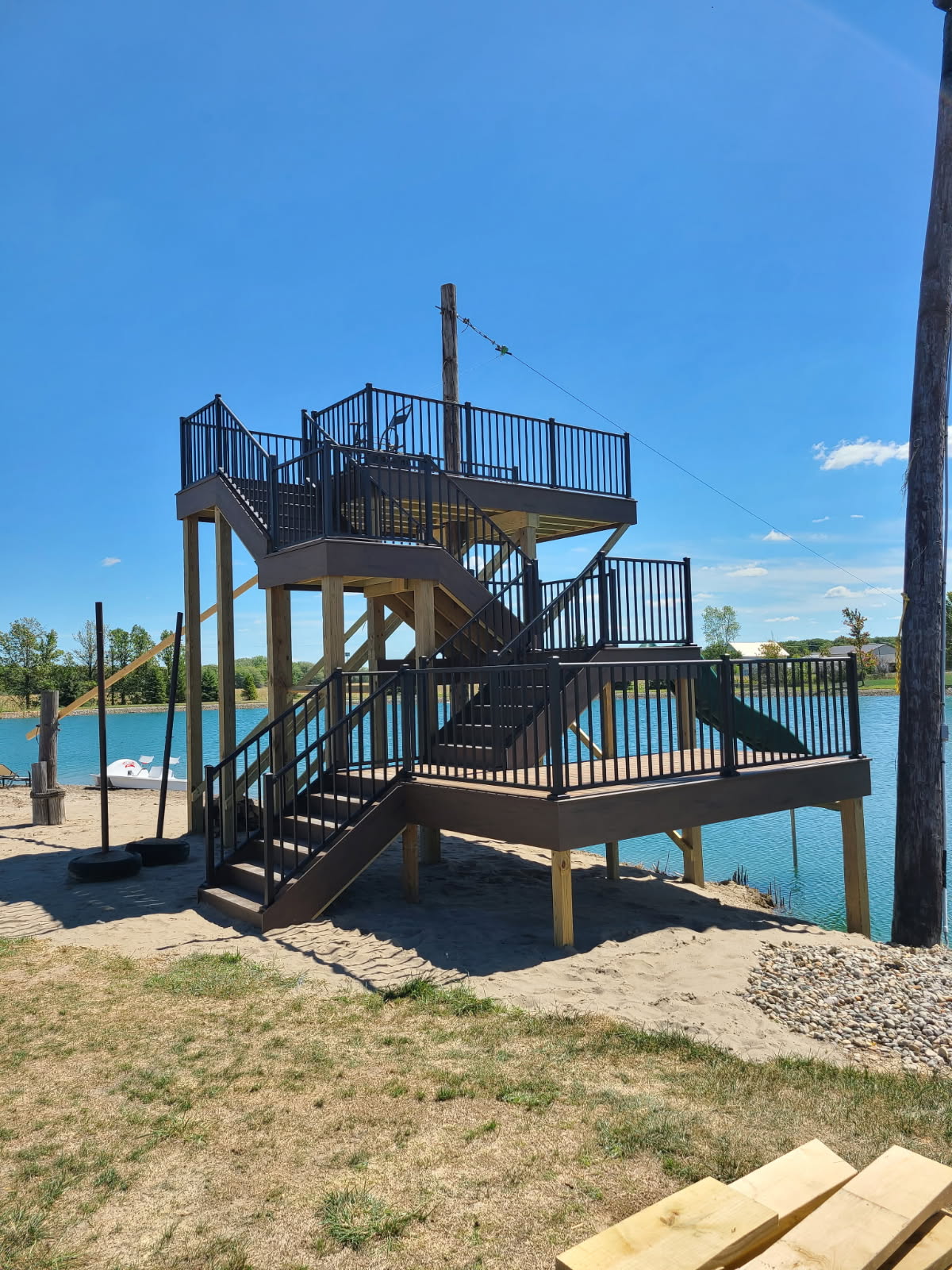 Two story lakeside observation deck with stairs and black aluminum railing built on a sandy beach