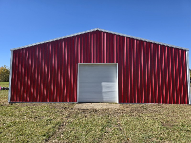 Front gable view of a red pole barn with white trim built by T&J Construction
