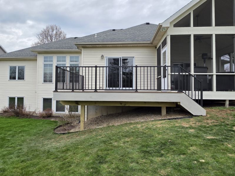 Elevated composite deck with black railing and stairs attached to a screened porch