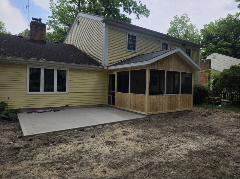 New screened porch addition with cedar siding and fresh concrete patio