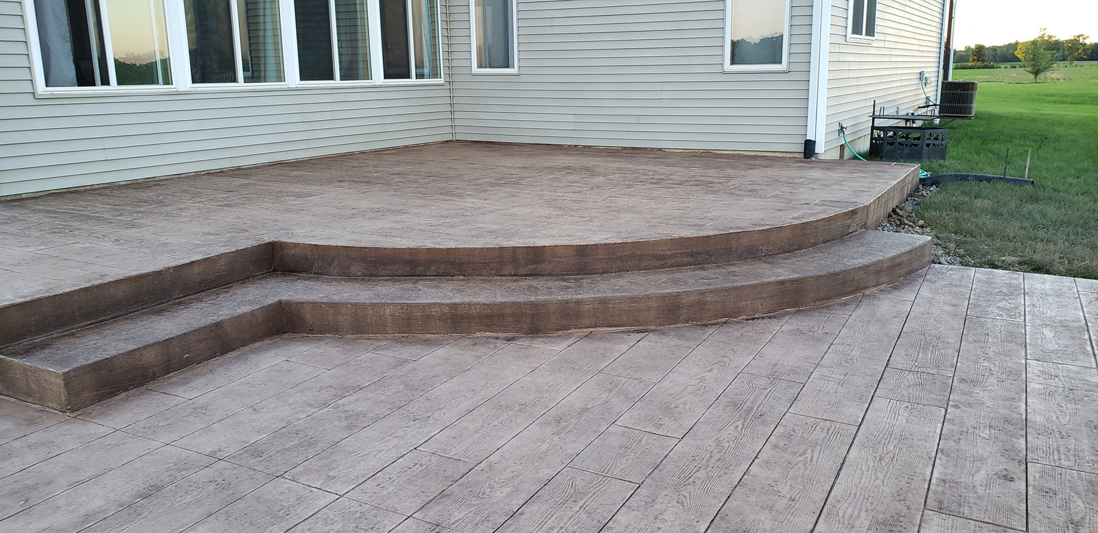 Large stamped concrete patio with wide steps in a wood plank pattern
